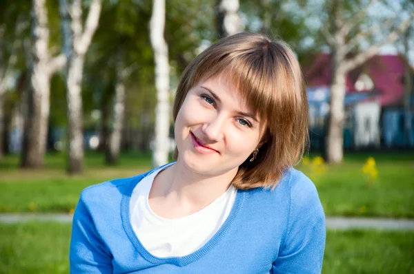 Usmívající se dívka sedící v parku — Stock fotografie