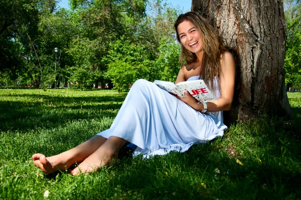 Giovane donna che legge libro nel parco — Foto Stock