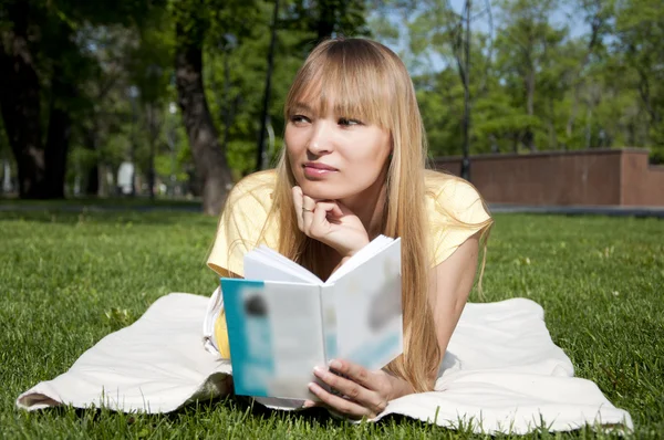 Νεαρή γυναίκα διαβάζει βιβλίο στο πάρκο — Φωτογραφία Αρχείου