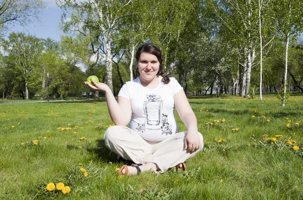 Woman sitting on the grass with an apple — Stock Photo, Image