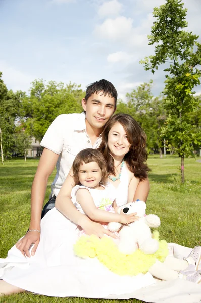 Retrato de la familia abrazándose en una hierba en el parque —  Fotos de Stock