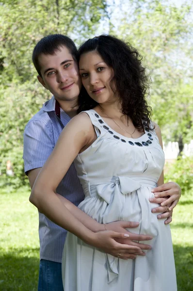 Man en een zwangere vrouw knuffelen in het park — Stockfoto