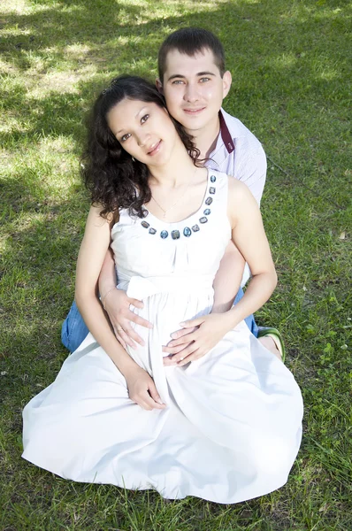 Мужчина и беременная женщина обнимаются в парке — стоковое фото