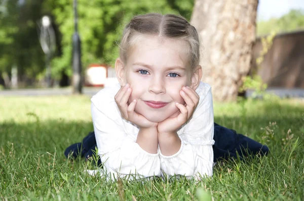Młoda dziewczyna leży na zielonej trawie i uśmiech — Zdjęcie stockowe