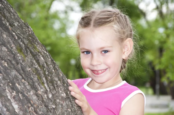 Dívka vykukovala přes strom — Stock fotografie