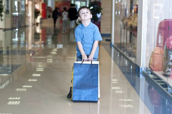 Little boy with the packages in the shop — Stock Photo, Image