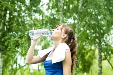 Genç kadın egzersizden sonra su içiyor.