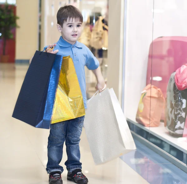 Little boy with the packages in the shop — Stock Photo, Image