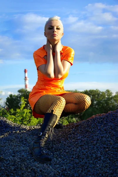 Blondes Mädchen in orangefarbenem PVC-Kleid — Stockfoto