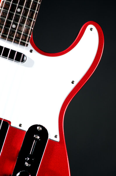 An electric metallic red guitar isolated on a black background in the vertical format with copy space.