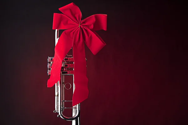 Zilveren trompet met rode strik op rood — Stockfoto