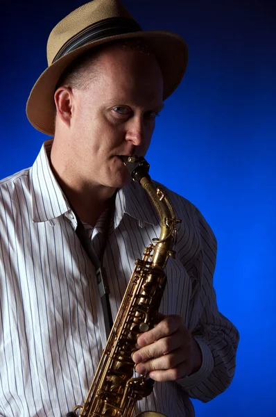 Saxofon hudebník a klobouk na modré — Stock fotografie