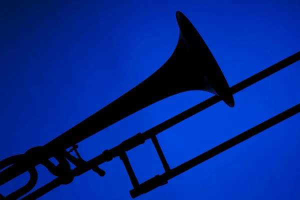 Trombone silhouet geïsoleerd op blauw — Stockfoto