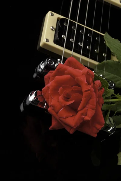 Rode roos op zwarte gitaar — Stockfoto