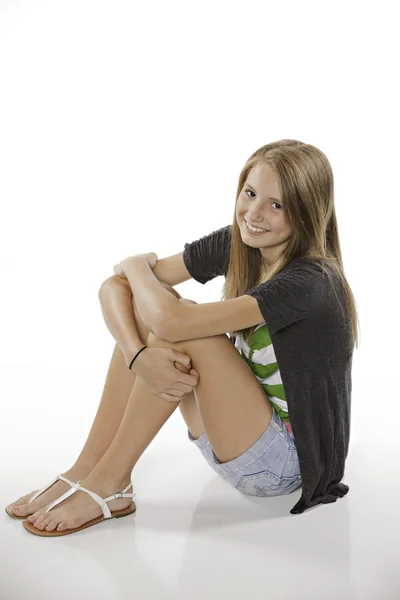 Šťastné dospívající dívka sedící na bílém pozadí — Stock fotografie