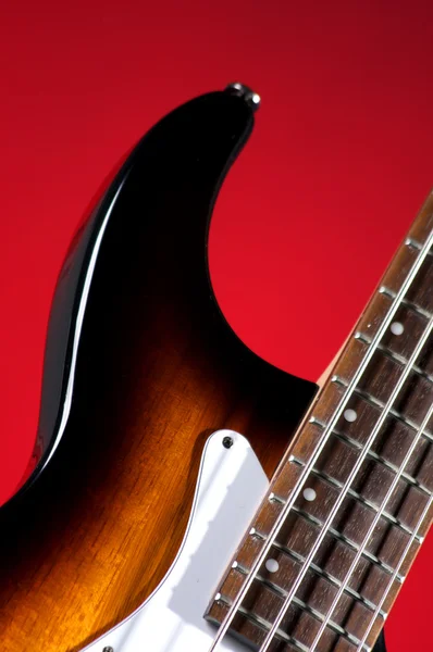 Elektrická basová kytara na červené — Stock fotografie