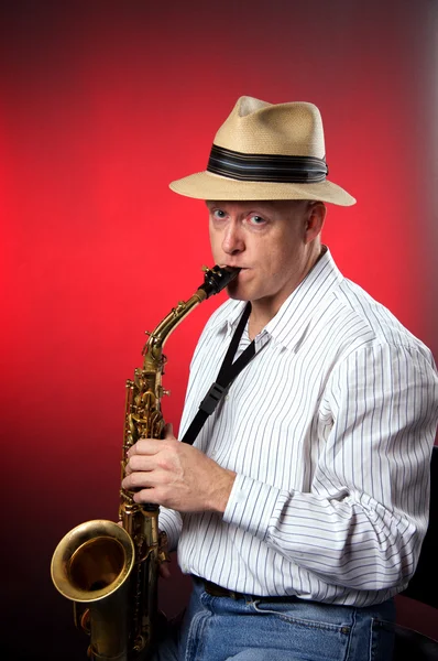 Saxofonist geïsoleerd op rood — Stockfoto