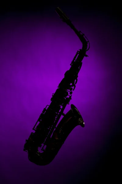 Саксофон силует ізольовано на фіолетовому — стокове фото