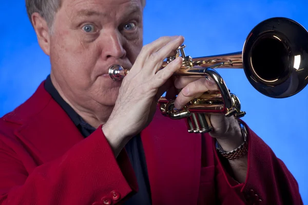 Senior man musicus trompet spelen op blauw Stockfoto