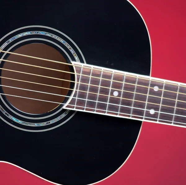 Černý akustická kytara na červené — Stock fotografie