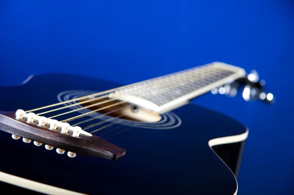 Zwarte akoestische gitaar op blauw — Stockfoto