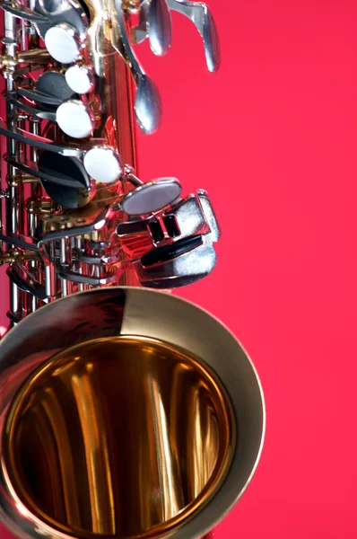 Guld-mässing saxofon isolerad på röd — Stockfoto