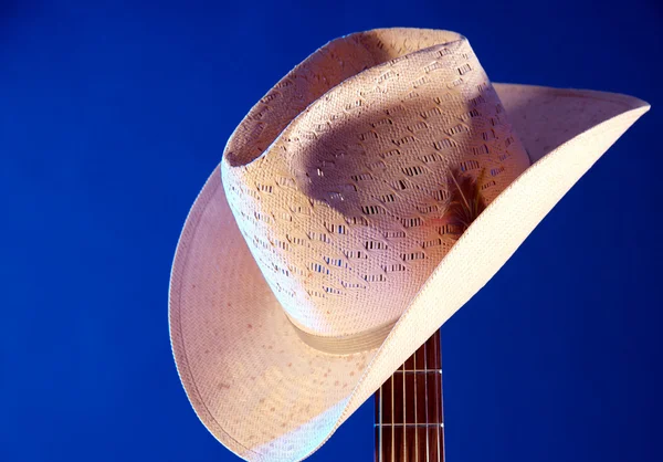 Westerse hoed op gitaar hals tegen blauw — Stockfoto