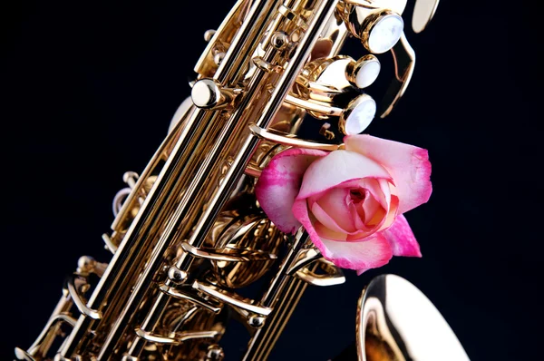 Goldenes Messingsaxophon und rosa Rose — Stockfoto