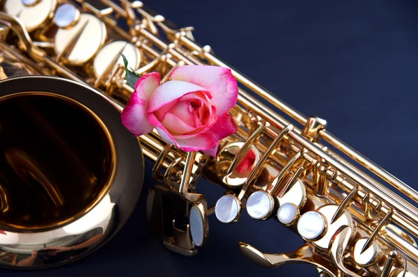 Goldsaxophon mit rosa Rose auf blau — Stockfoto