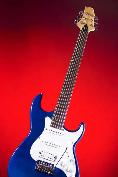 Μπλε κιθάρα που απομονώνεται ενάντια κόκκινο — Φωτογραφία Αρχείου