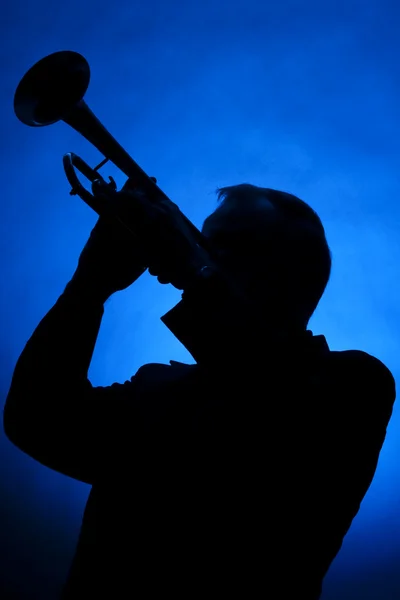 Trompet musicus silhouet op blauw Stockfoto
