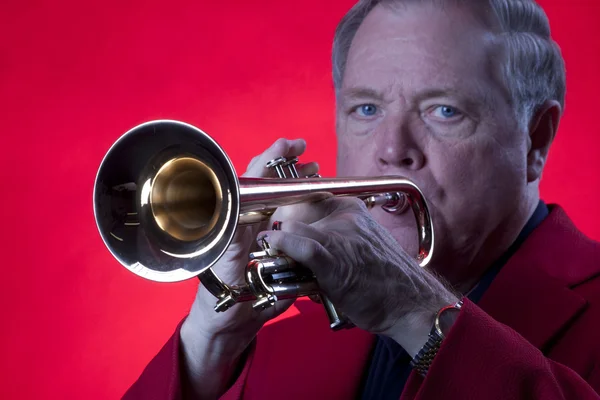 Músico tocando trompete isolado no vermelho — Fotografia de Stock