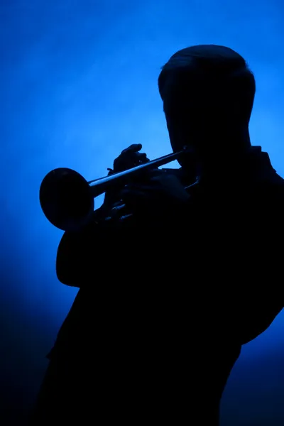 Trumpet spelaren silhuett mot blå plats ljus — Stockfoto