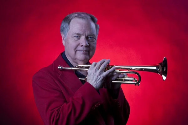 Musicus bedrijf trompet op rood — Stok fotoğraf