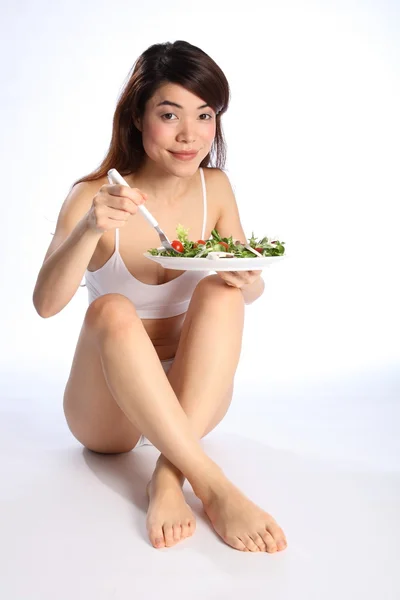 Menina oriental bonita comer salada — Fotografia de Stock