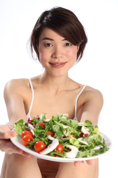 Girl holds out plate of green salad — Stock Photo, Image