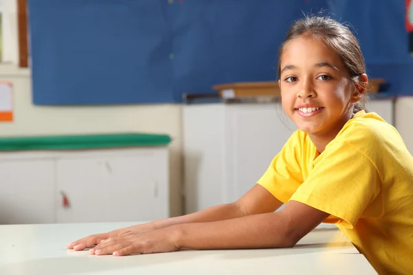 Glücklich lächelndes Schulmädchen 10 in Gelb an ihrem Schreibtisch — Stockfoto
