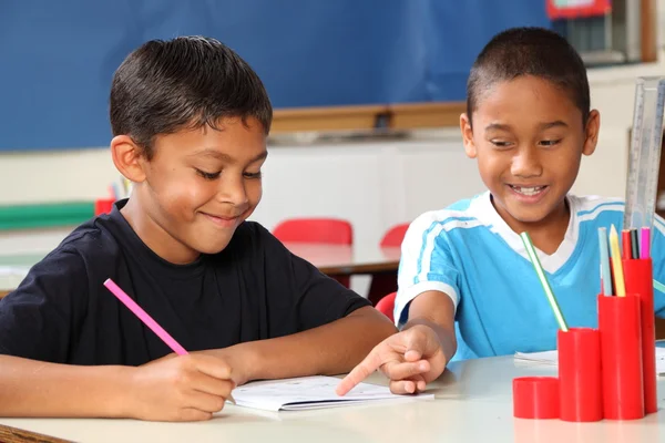 Two schoolboys helping each other learn in class during lessons Stock Photo
