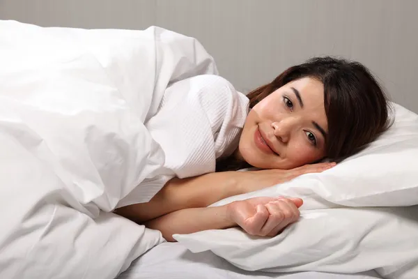 Mulher deitada na cama sorrindo — Fotografia de Stock