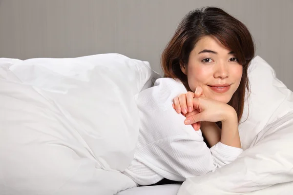 Mujer joven relajante en cama sonriendo — Stok fotoğraf