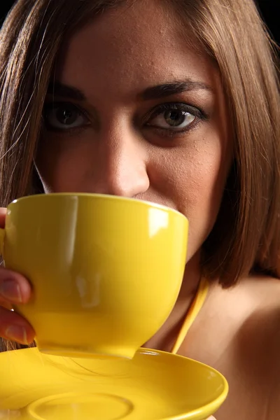 Woman drinking from a yellow cup of tea — Stock Photo, Image