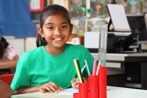 Schulmädchen lächeln im Unterricht am Schreibtisch — Stockfoto