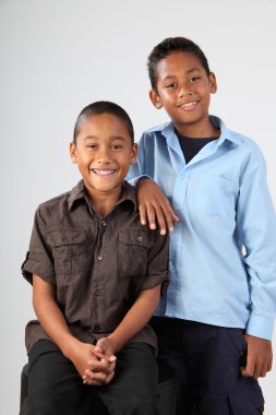 Two school boys pose happily together in studio clipart