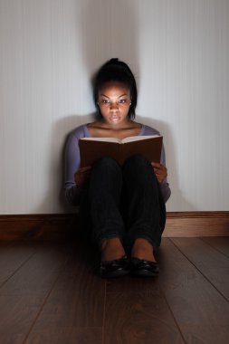 Girl reading horror story book looking frightened clipart