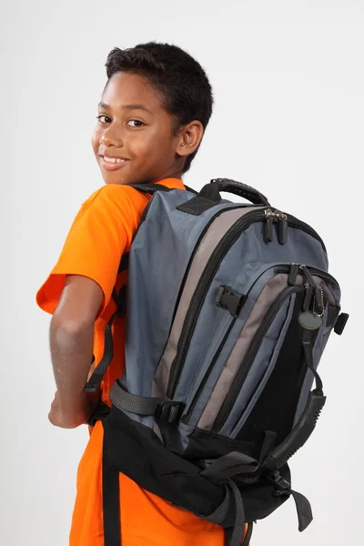Heureux écolier ethnique portant un sac — Photo