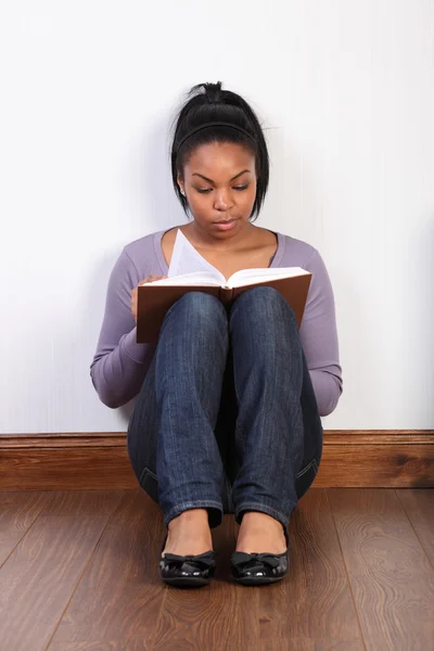 Schöne Frau sitzt auf dem Boden und liest ein Buch — Stockfoto