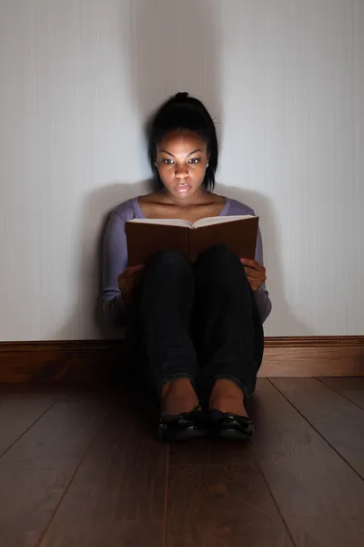 Girl reading horror story book looking frightened — Stock Photo, Image