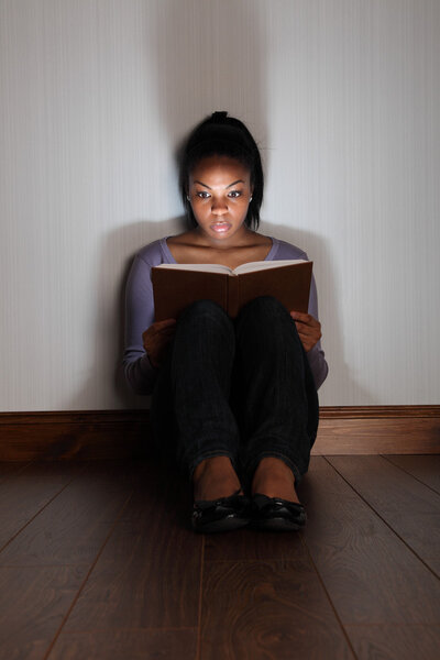 Girl reading horror story book looking frightened