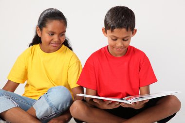 Two school kids reading a book clipart