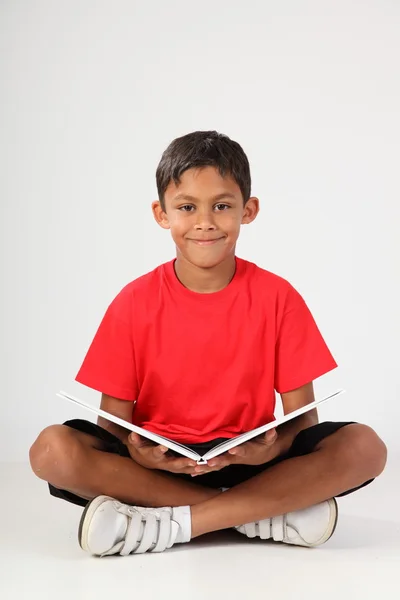 Genç bir çocuk kitabı okurken mutlu bir gülümseme — Stok fotoğraf